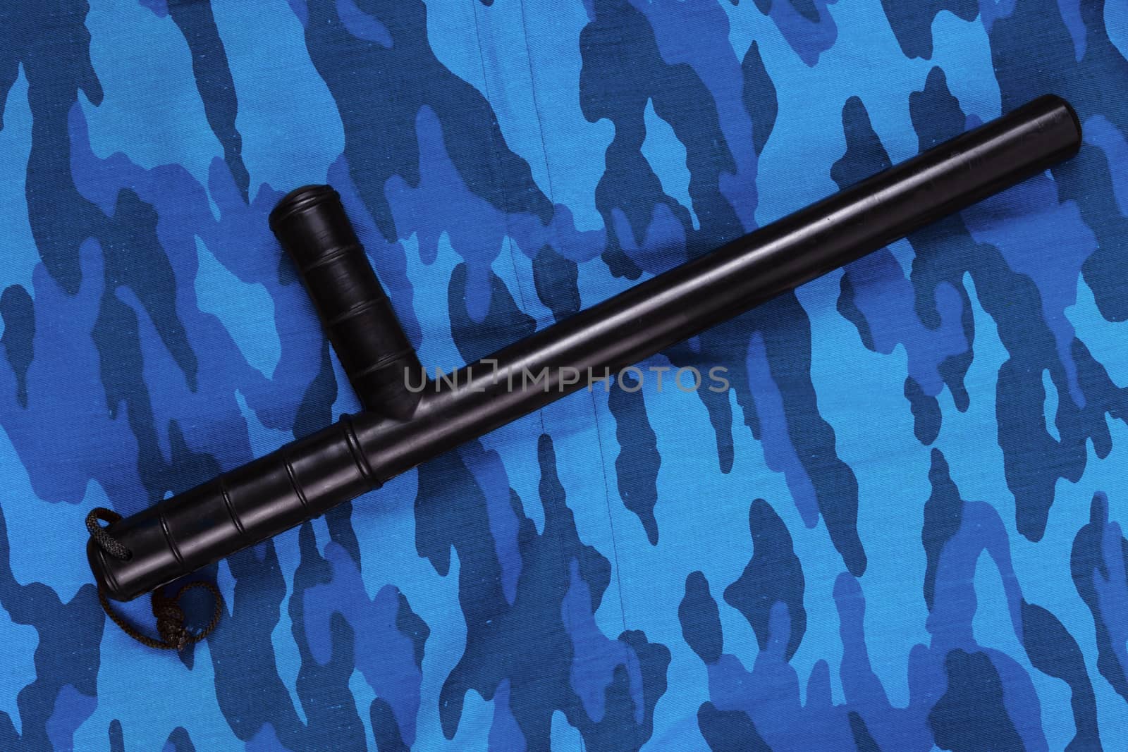 black rubber baton on blue urban russian riot police camouflage flat lay top-down perspective.
