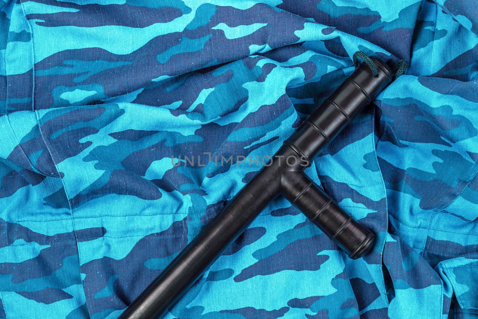 black rubber baton on blue urban russian riot police camouflage flat lay top-down perspective.