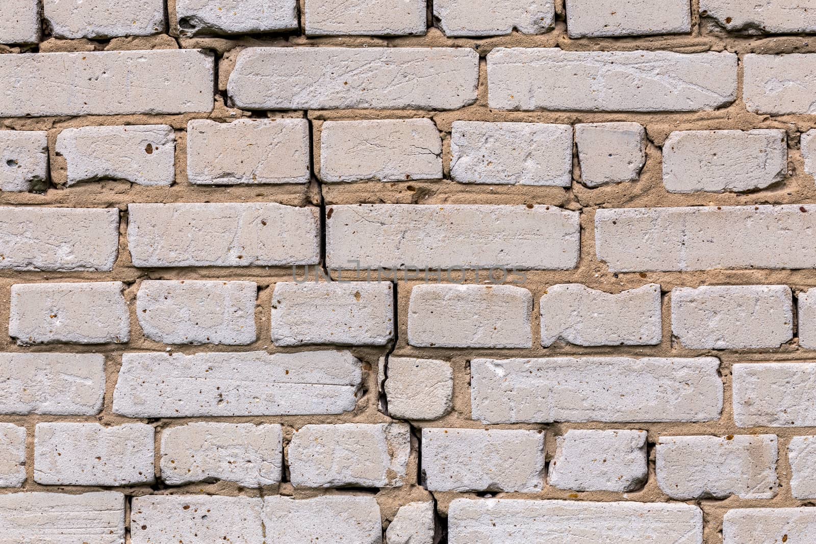 Deep cracked white silicate brick wall closeup texture and background. Horizontal shot.