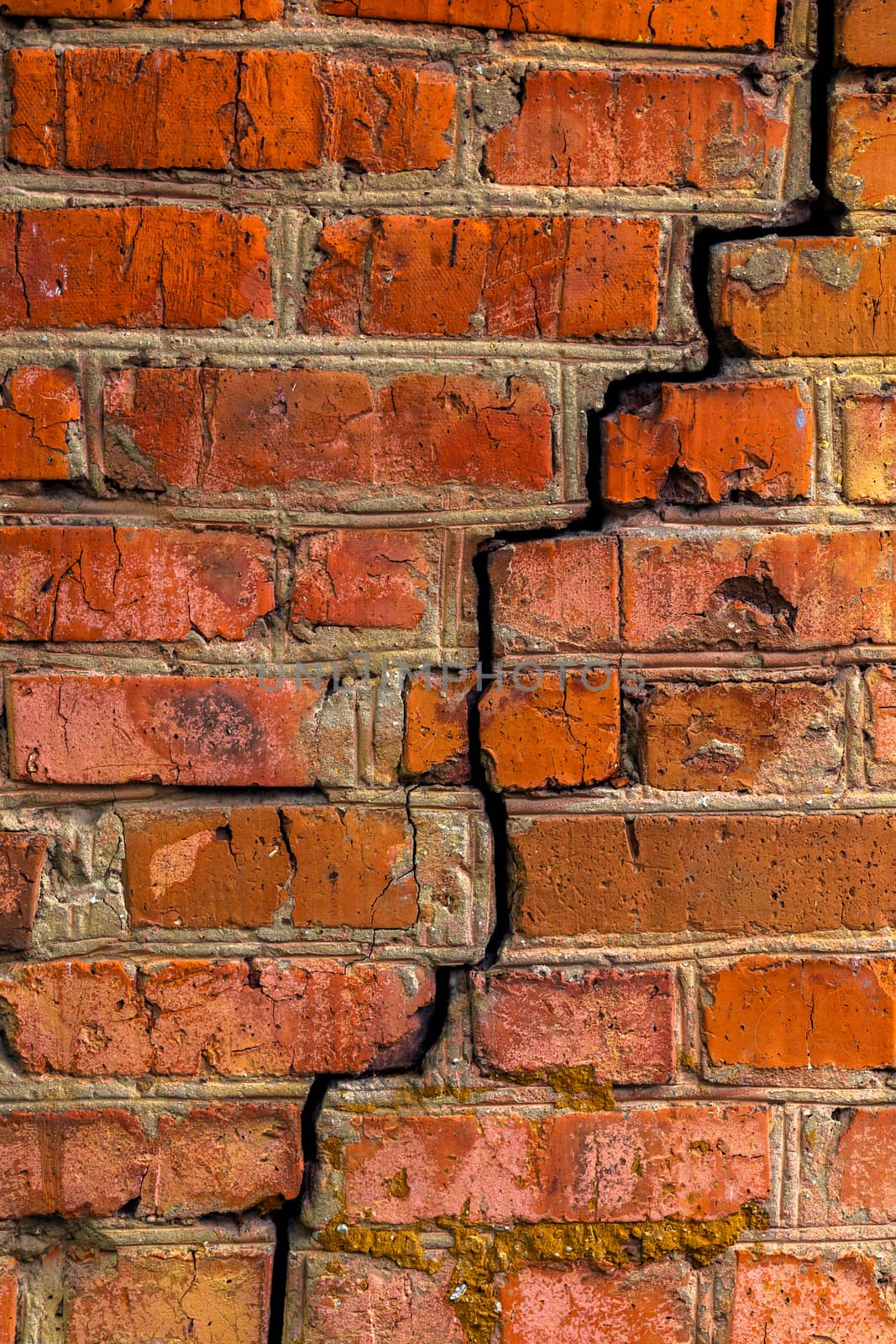 Deep cracked orange brick wall closeup texture and background. Vertical shot.