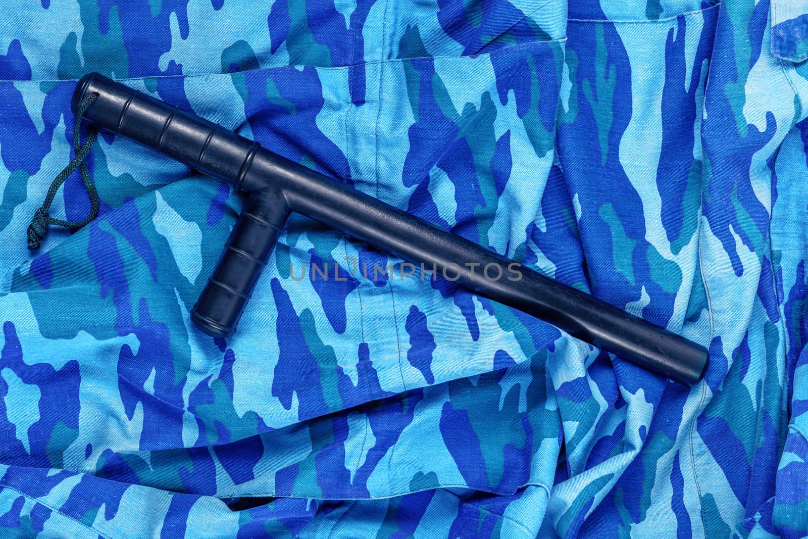 black rubber baton on blue urban russian riot police camouflage flat lay top-down perspective.