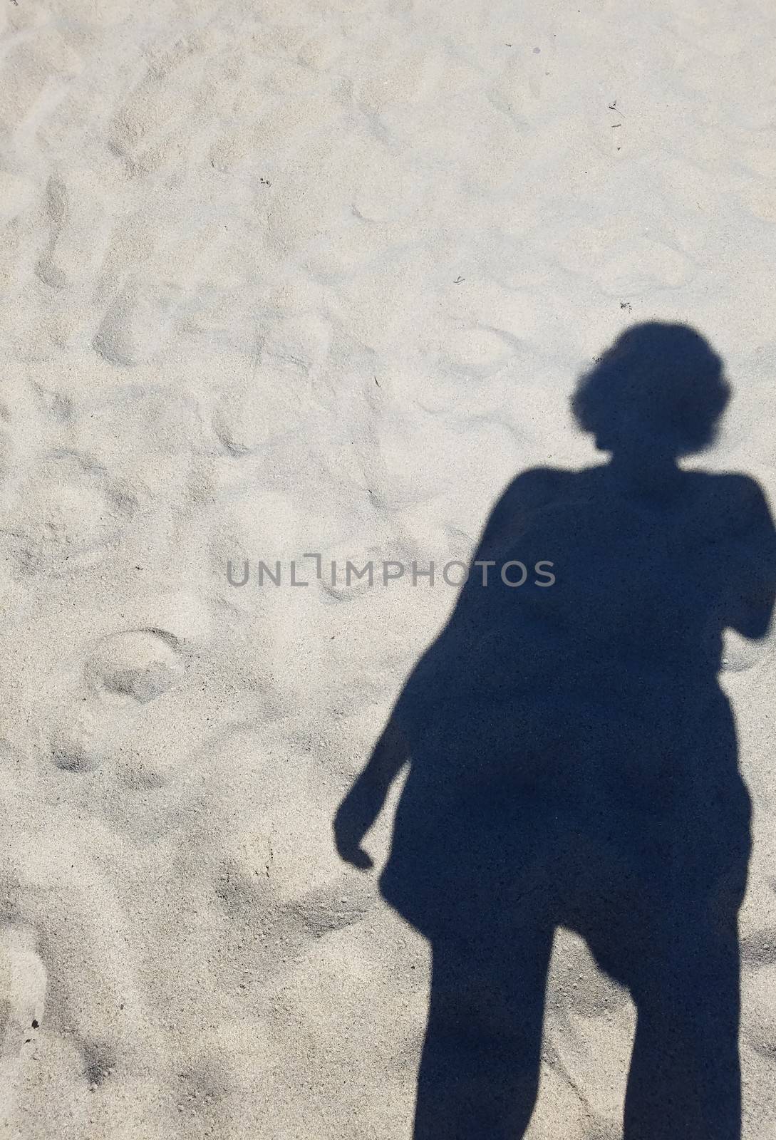 shadow or silhouette of woman or girl in sand at beach