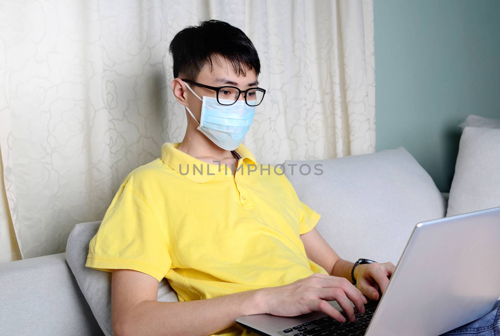 An asian man is working from home during pandemic coronavirus  Covid-19. Ccoronavirus covid 19 infected patient in quarantine room using computer.



