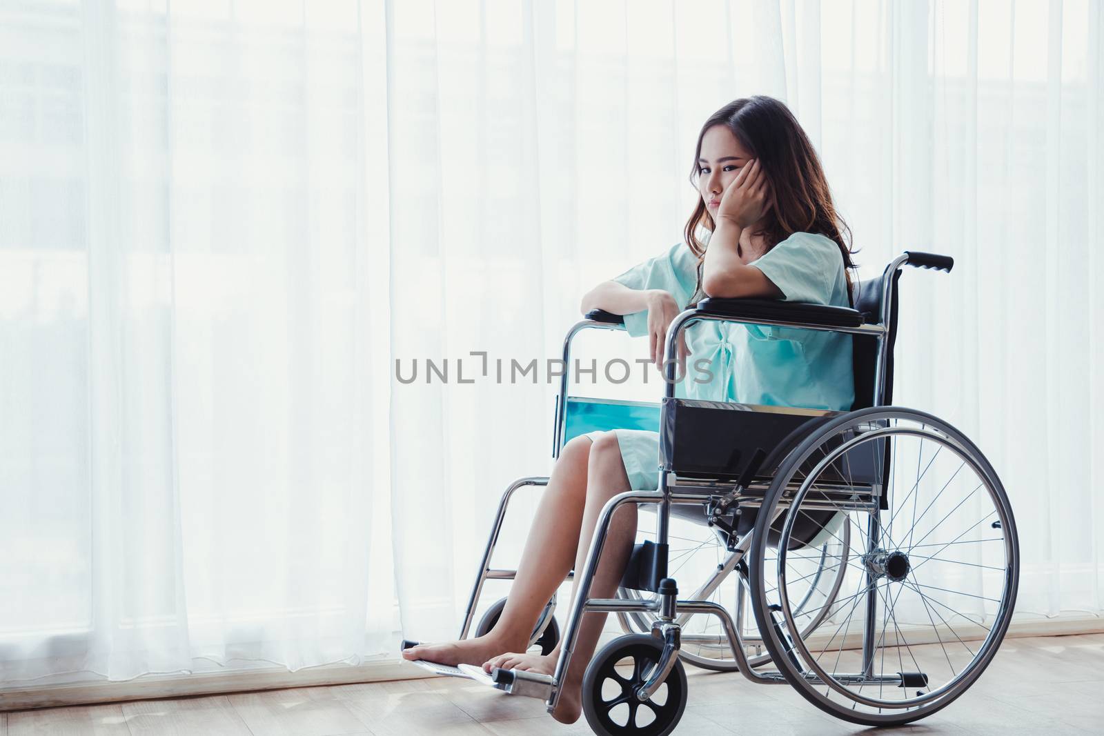 Female patient who have been admitted for a long time are sitting in a wheelchair with a facial bored at the hospital.