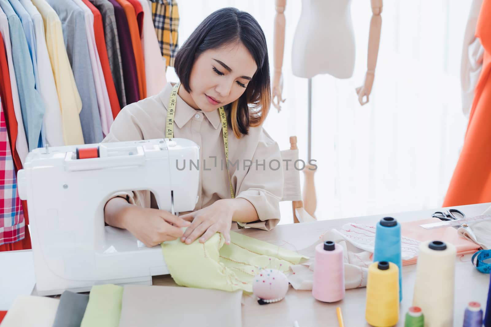 Professional fashion designers are cutting new clothes using sewing machines in studio. Designer using sewing machine in working. Startup designer concept.
