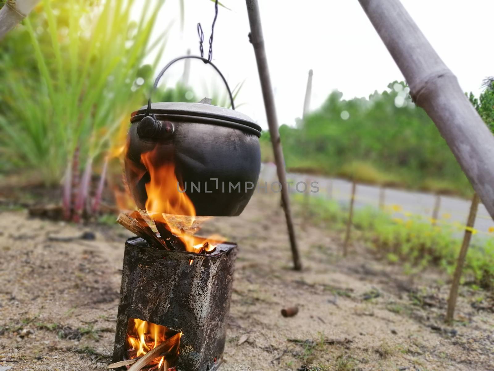 Food preparing and cooking  in field conditions with blur background.Boiling pot at the campfire on picnic in the forest during summer holiday.