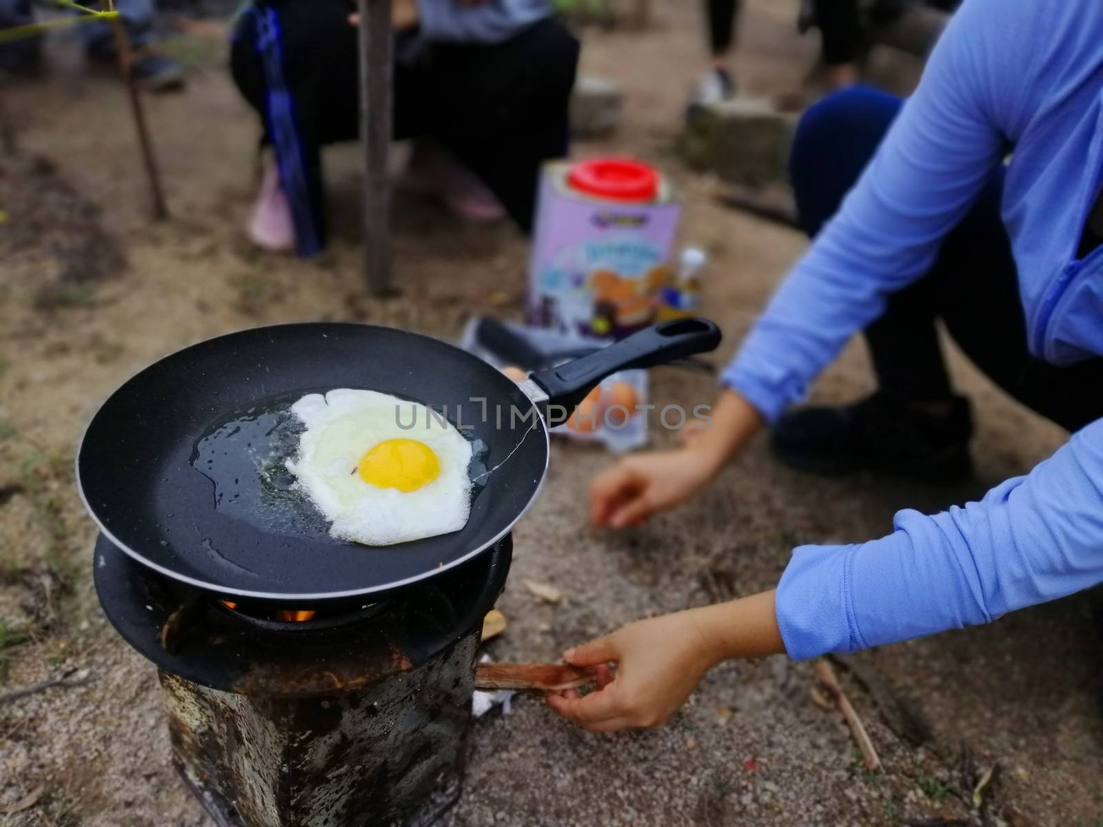 Cooking breakfast on campfire in cast iron pan with selective focus.