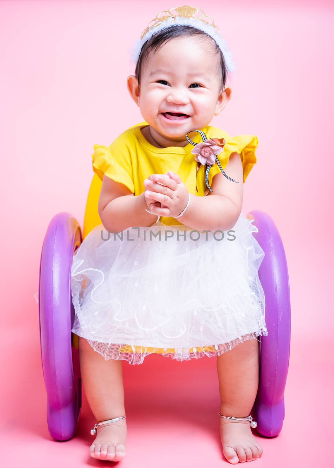 Portrait of Asian princess little baby girl happy face in beautiful dress sitting on the chair she is a smile in the studio isolated on pink background, Baby 9 months