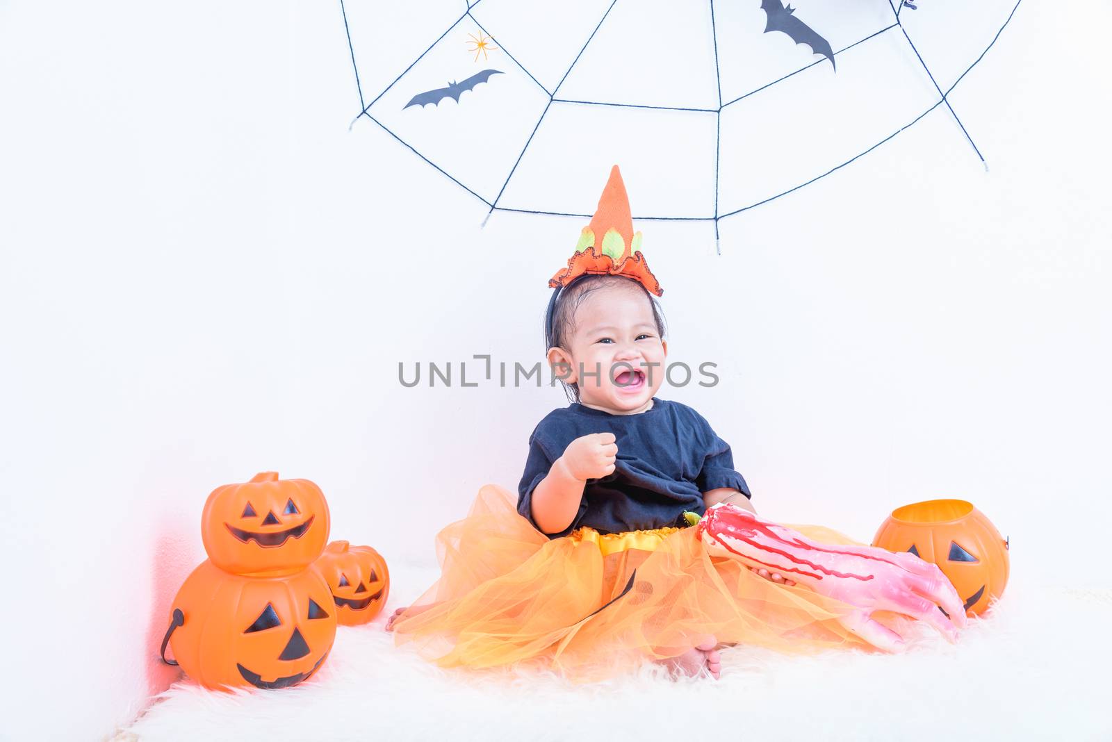 Funny happy baby girl in Halloween costume with pumpkin Jack by Sorapop