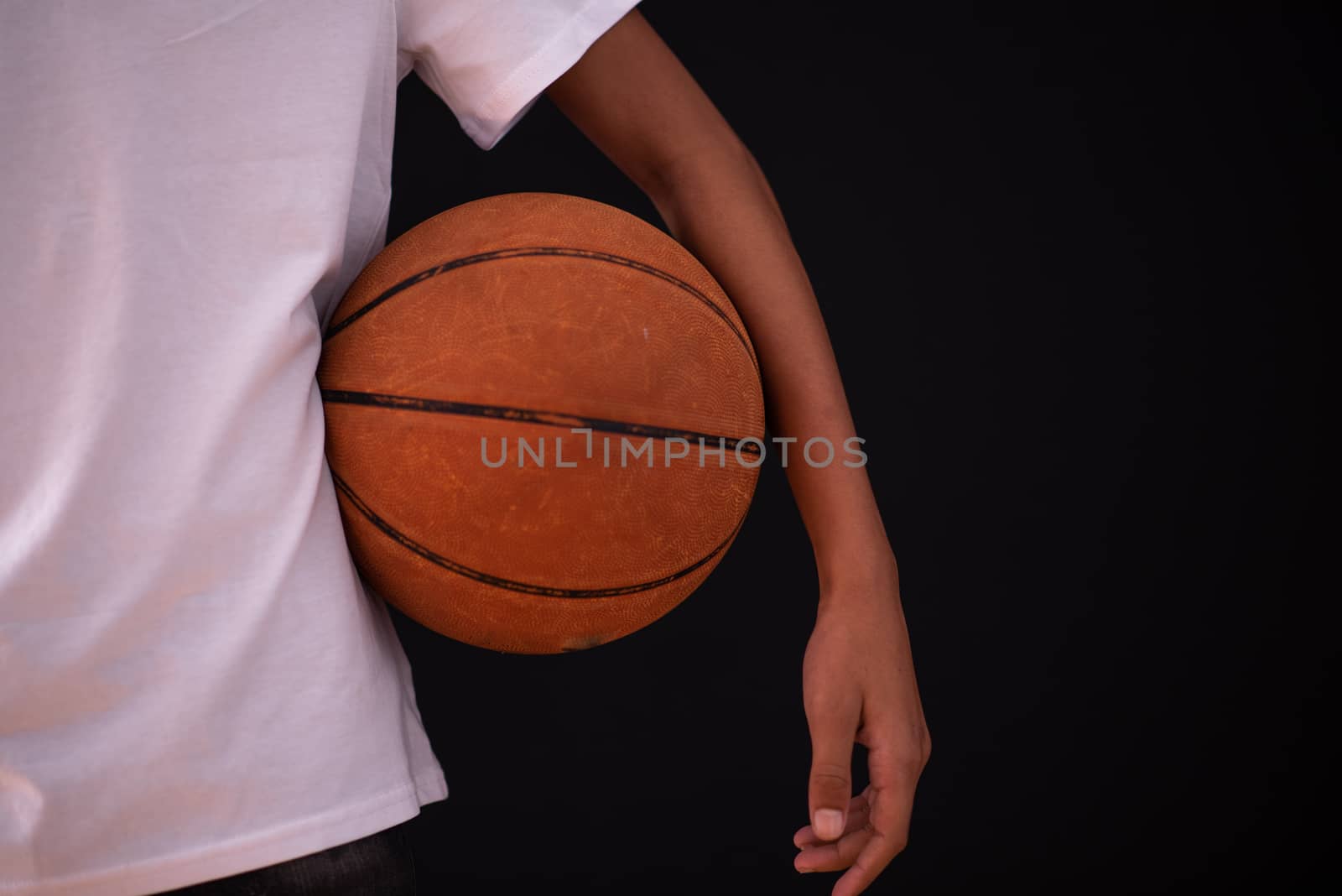 Young person standing with basketball under his arm