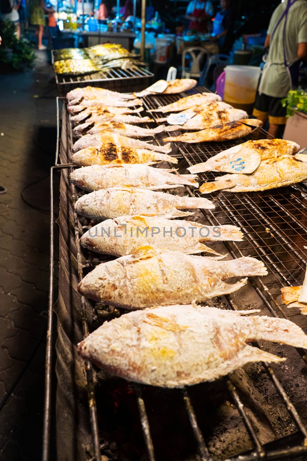 Asian food. Counter with fish in salt on the grill at a night food street market. by Try_my_best