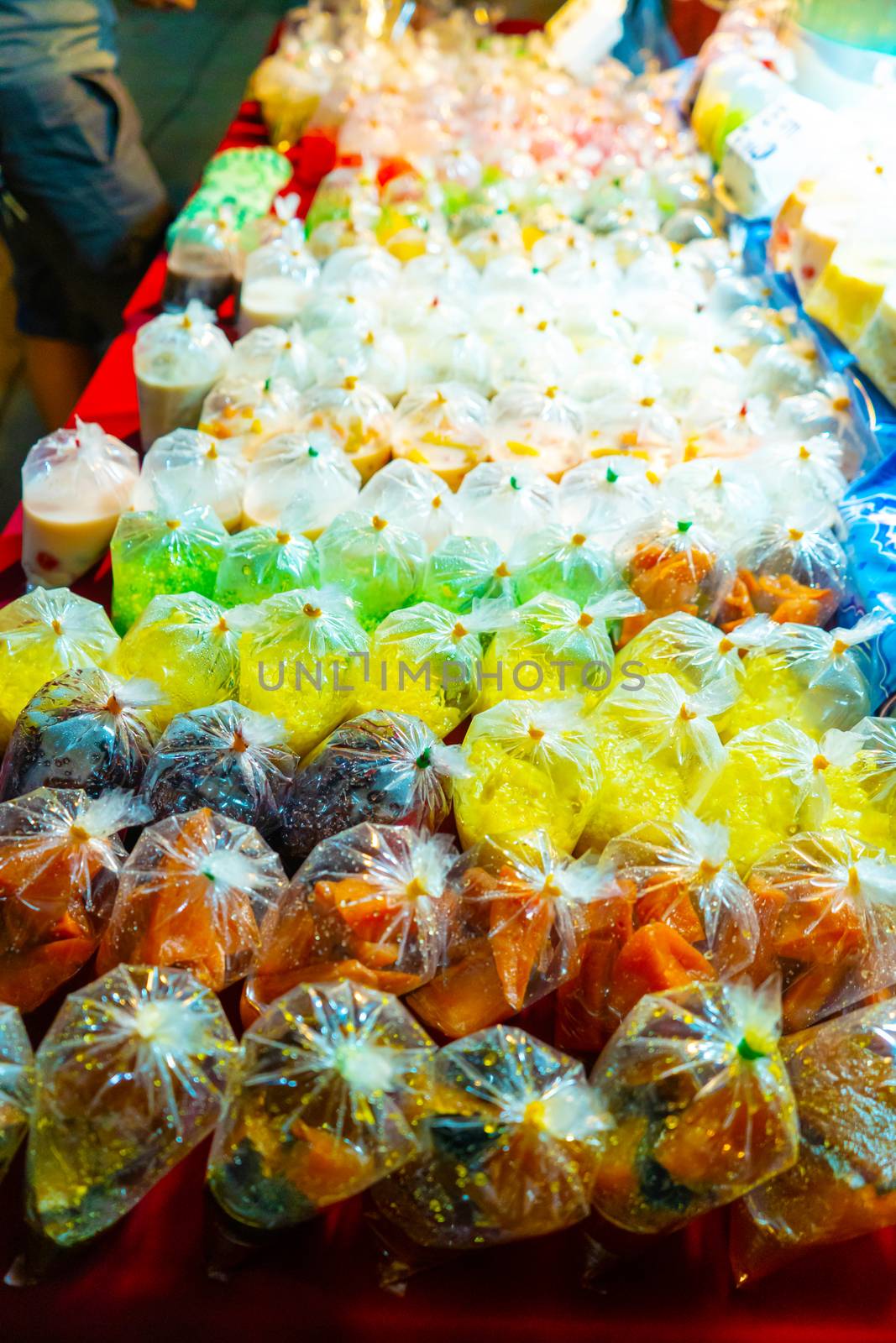 Colored desserts in plastic bags at a street food market in Asia. Unusual Asian food