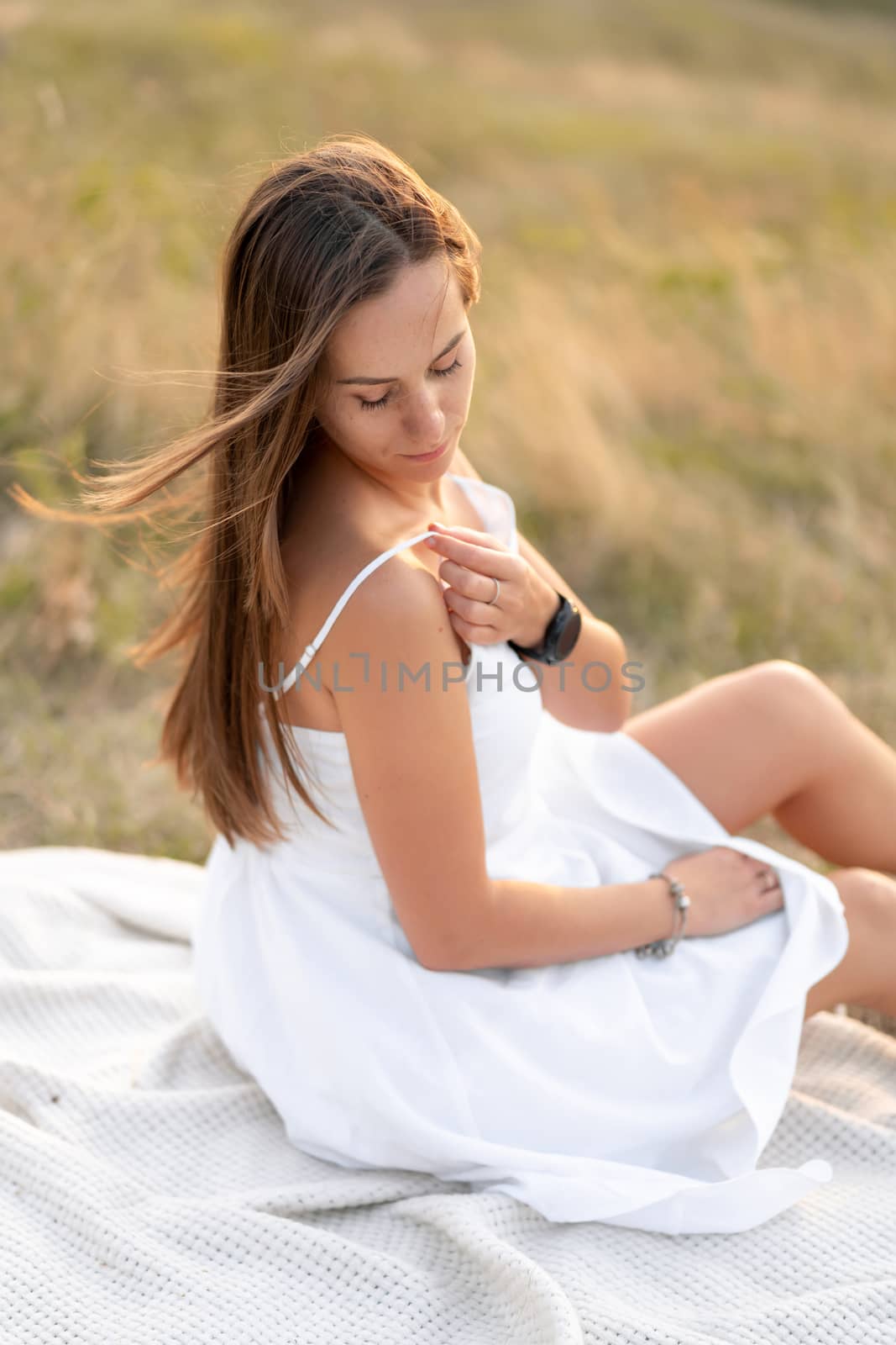 Portrait of a beautiful young tender brunette girl in a white sundress, in nature.