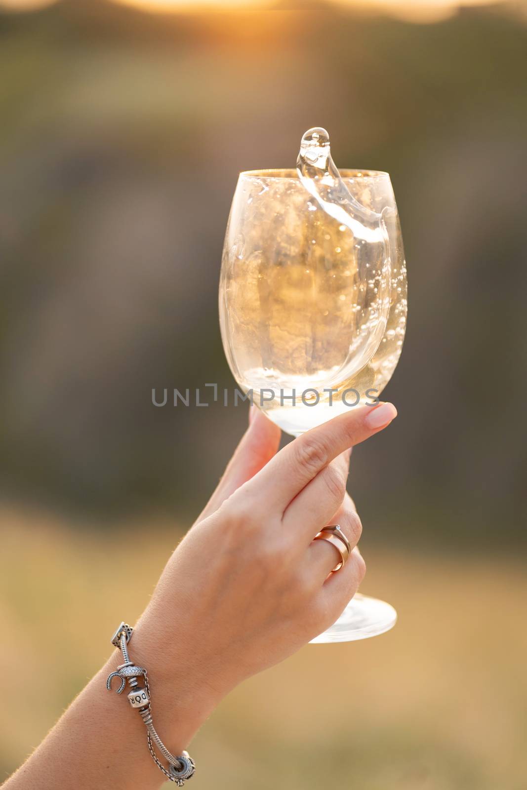 Girl churns wine in a glass at sunset