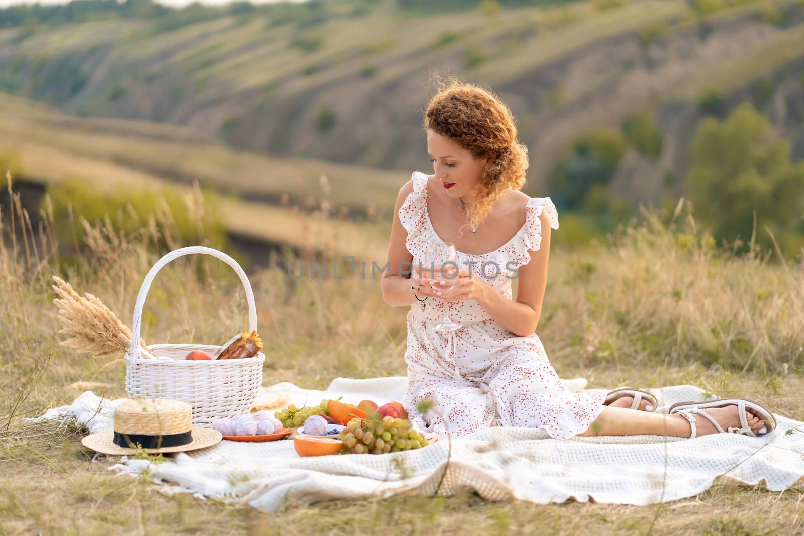 Beautiful girl on a picnic in a picturesque place. Romantic picnic.