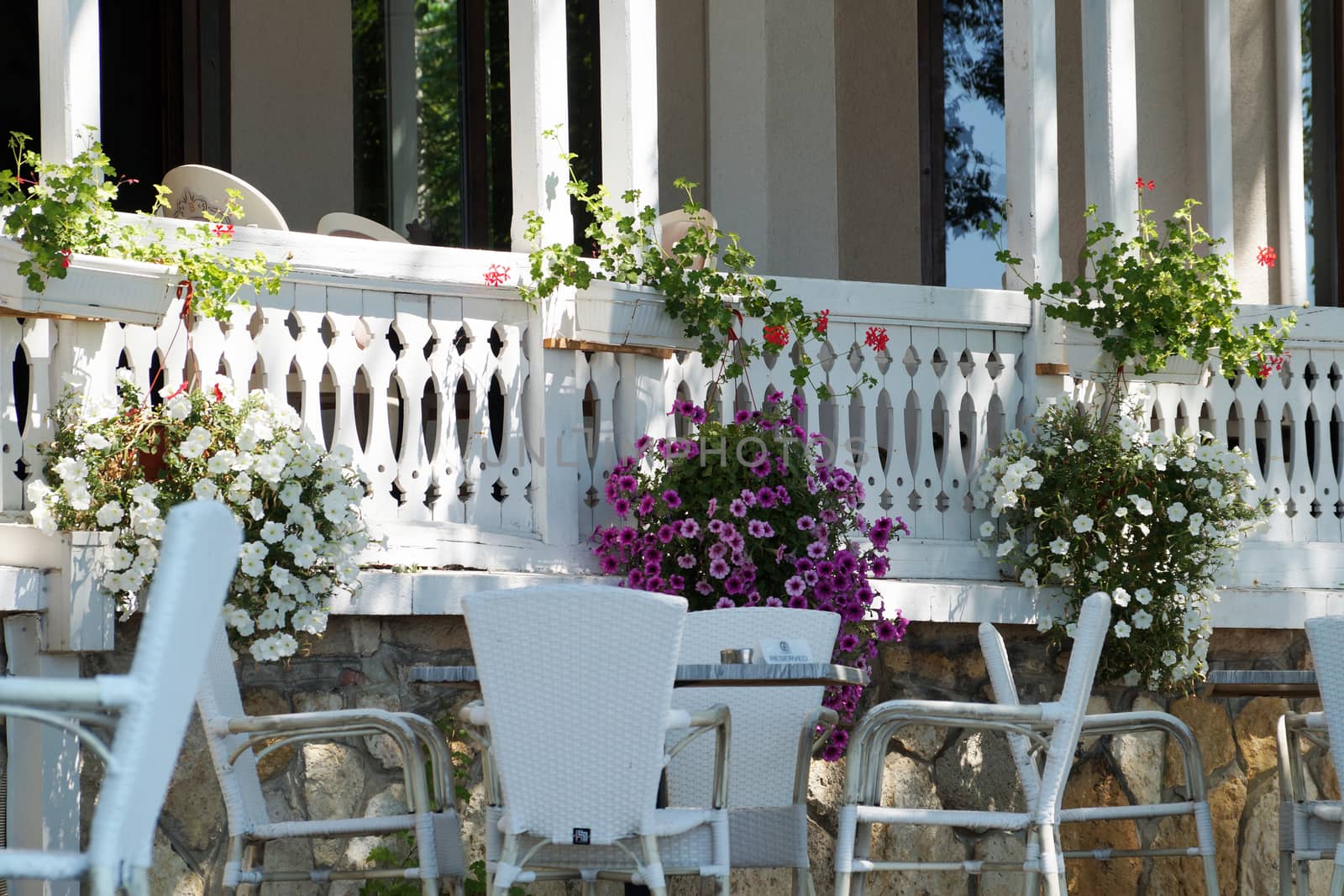 white terrace in Provence style with flower pots and white table with chairs