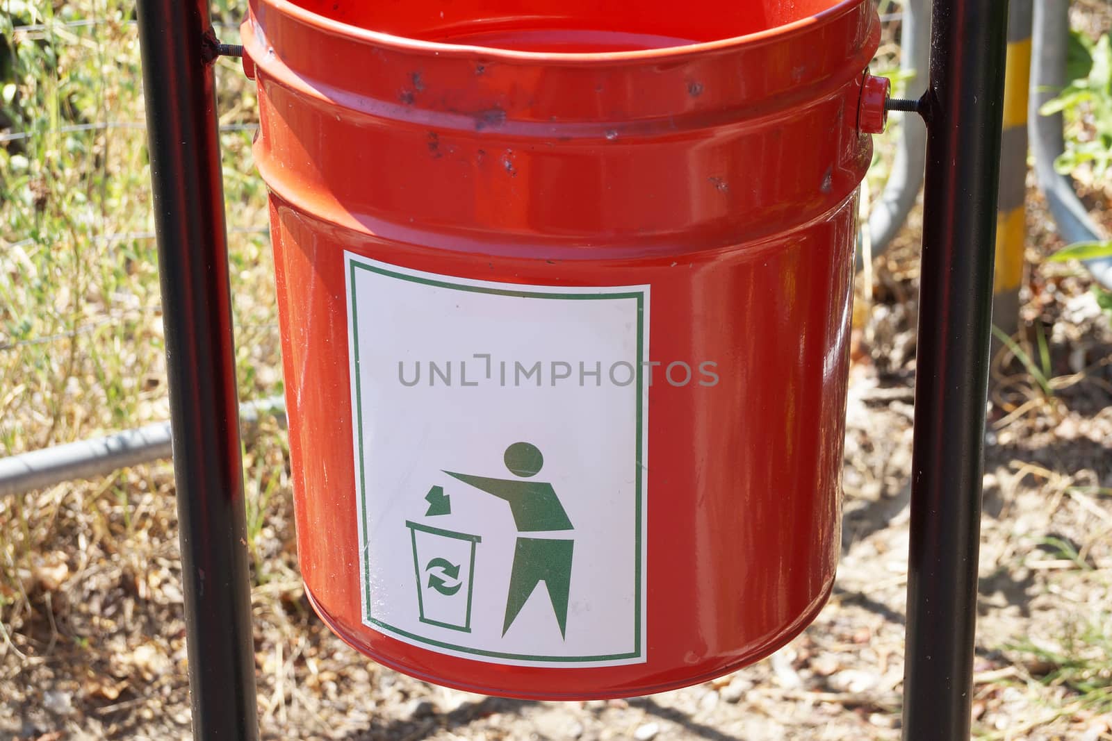 red metal trash can in the park close up by Annado