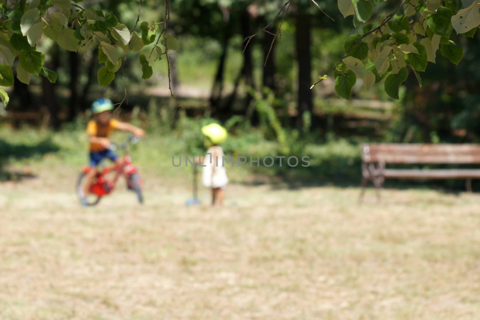 blurred photo, little children in the park with a bike and scooter