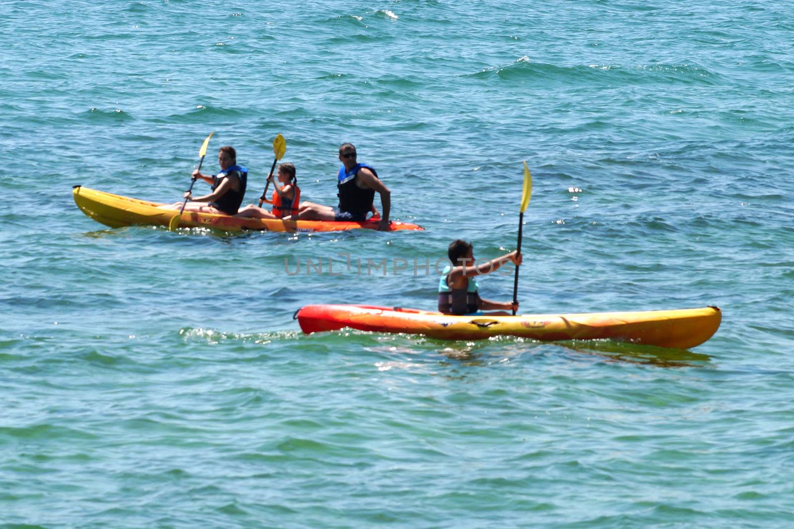 family kayaking on the sea on sunny day by Annado