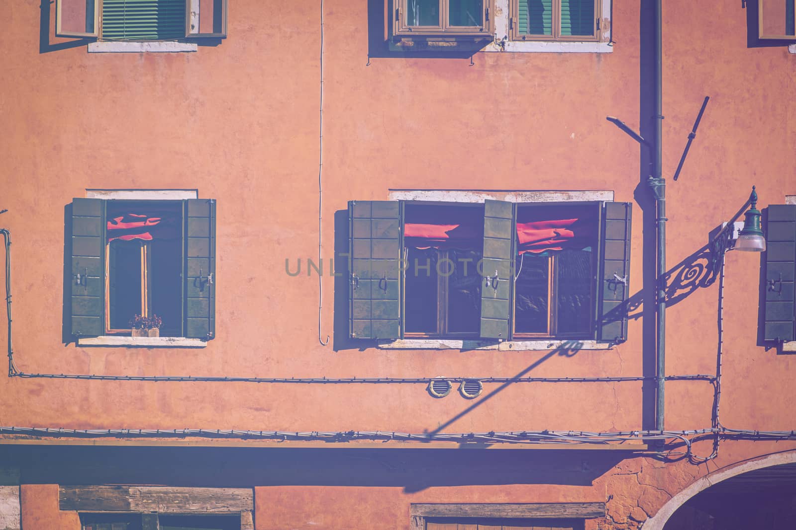 Italian culture on Venetian facades in faded color effect. Venice is rich and poor, well-groomed and abandoned, reflected in its windows.