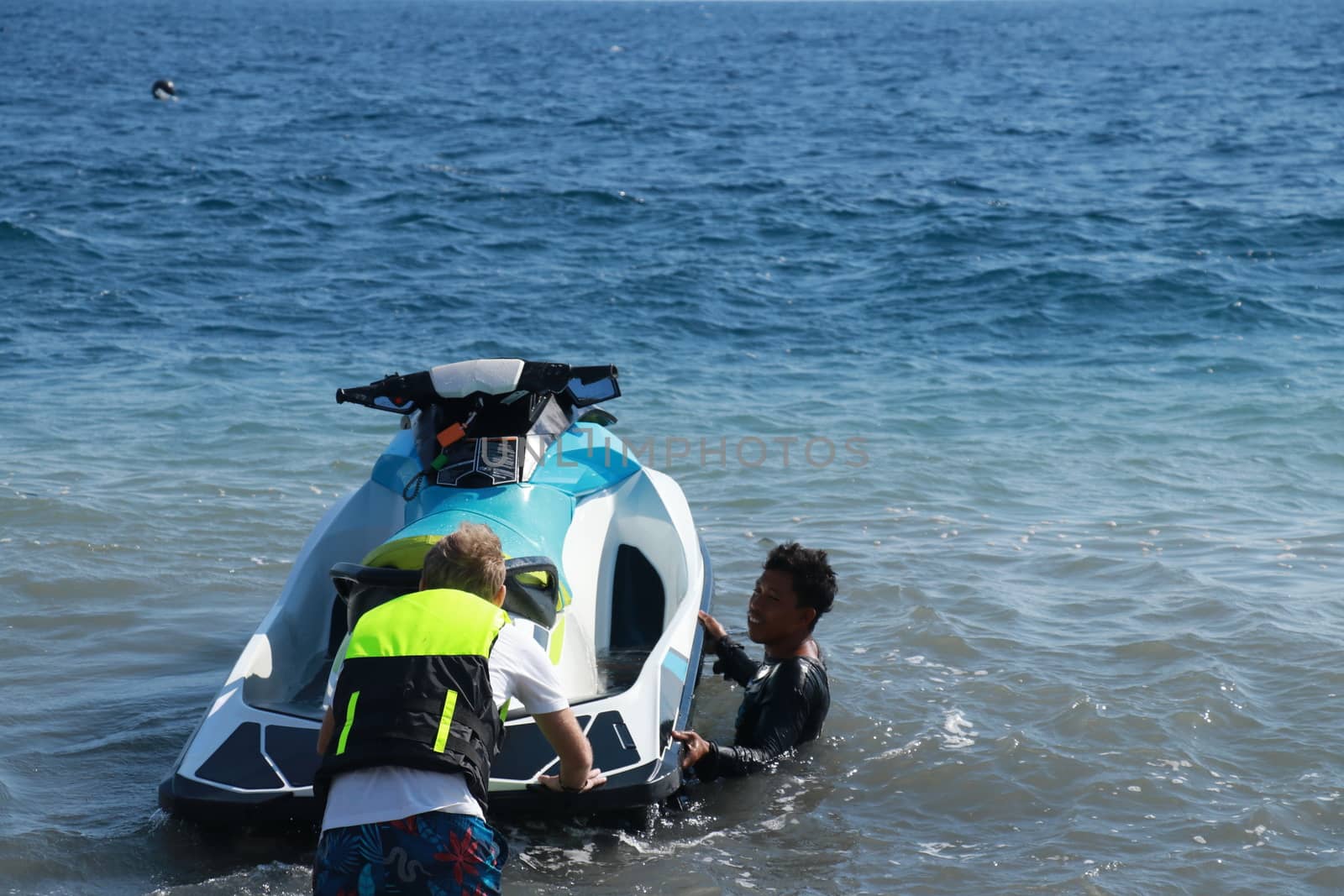 Man Take a water bike for ride. Wwatercrafts and wave runners are having fun on a sunny day. The instructor explains to the customer how to drive a jet ski.