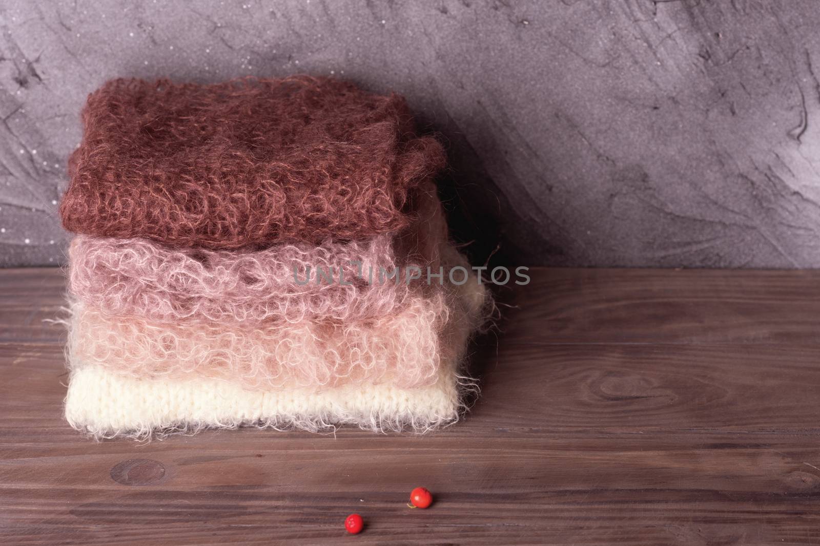 the pile of pastel wool scarves on the wooden background