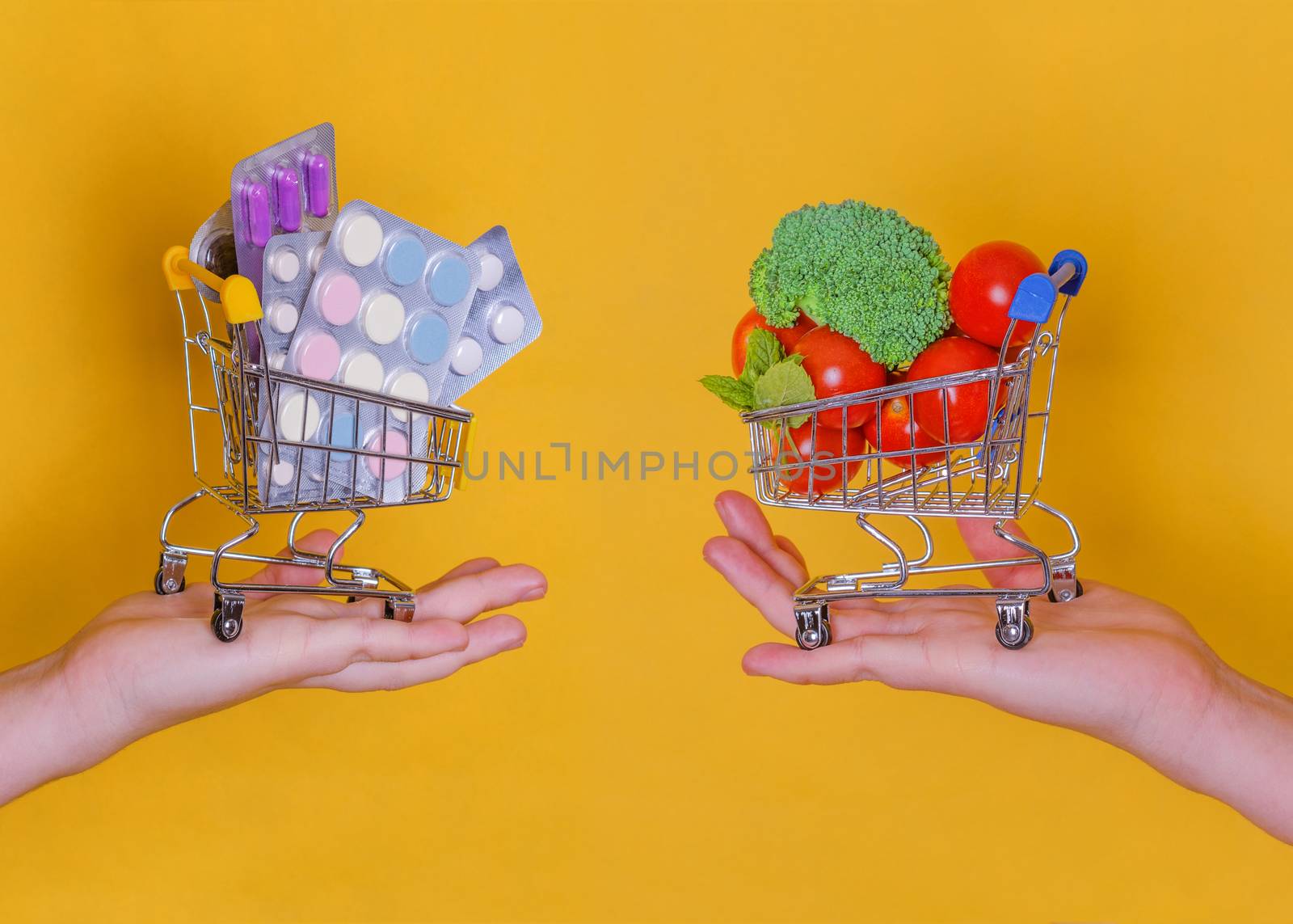 Hands holding shopping carts with vegetables and tablets on a yellow background, the concept of choosing healthy food and disease
