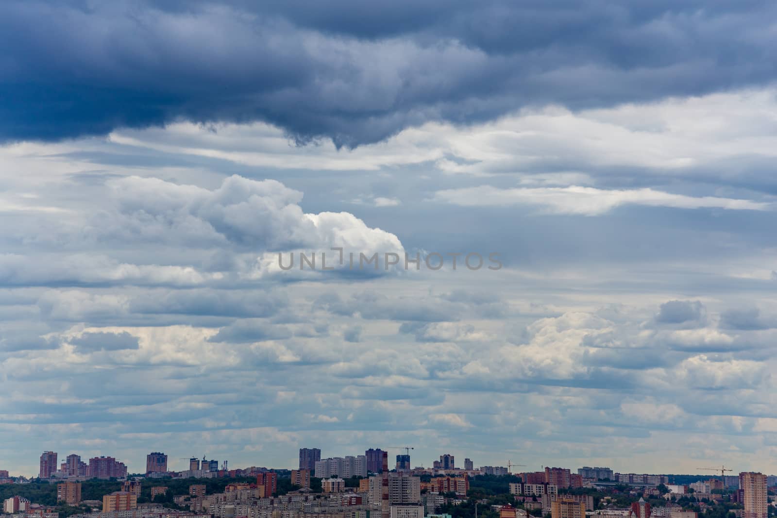 russian summer daylight cityscape with large cumulus clouds and tiny horizon line of the panel condominium houses.