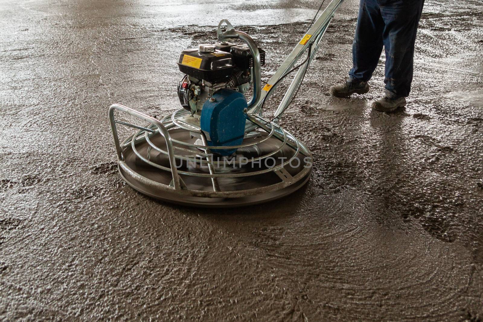 Power float grinder machine on wet concrete background closeup shot with selective focus and boke blur.