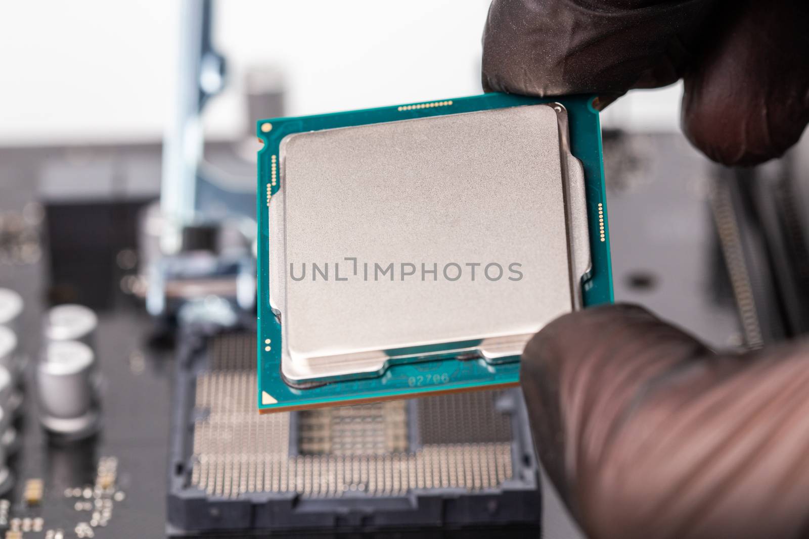 hand in black glove installing central processor unit in pc motherboard - closeup with selective focus and blur