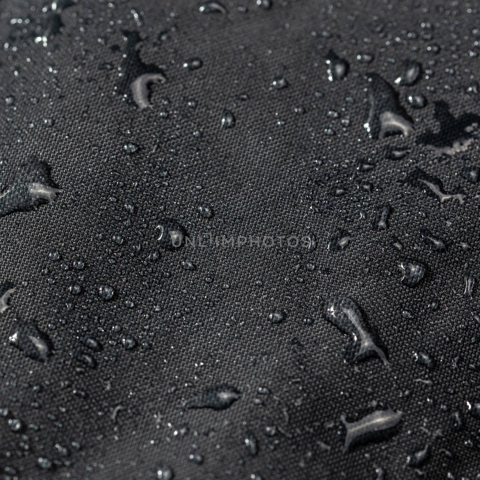 dark gray waterproof hydrophobic cloth closeup with water drops selective focus background by z1b