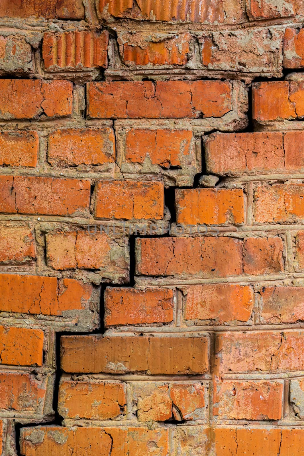 Deep cracked orange brick wall closeup texture and background. Vertical shot.