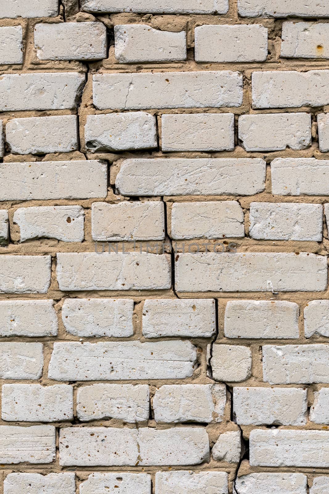 Deep cracked white silicate brick wall closeup texture and background. Vertical shot.