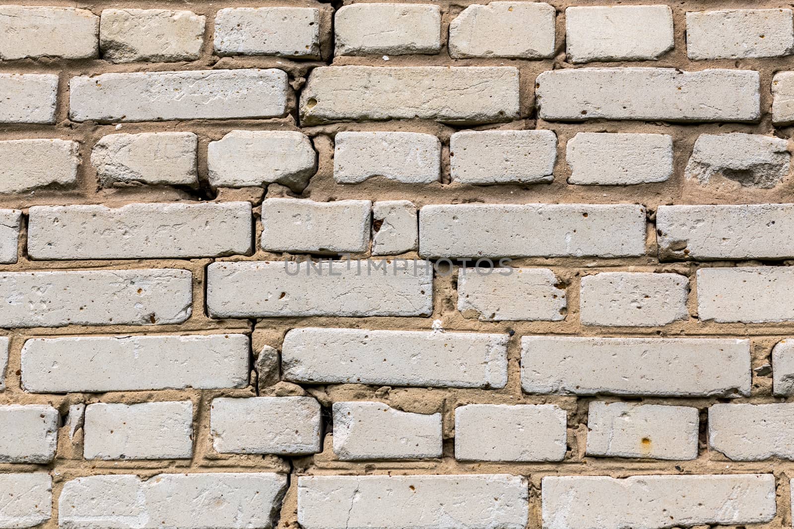 Deep cracked white silicate brick wall closeup texture and background. Horizontal shot.