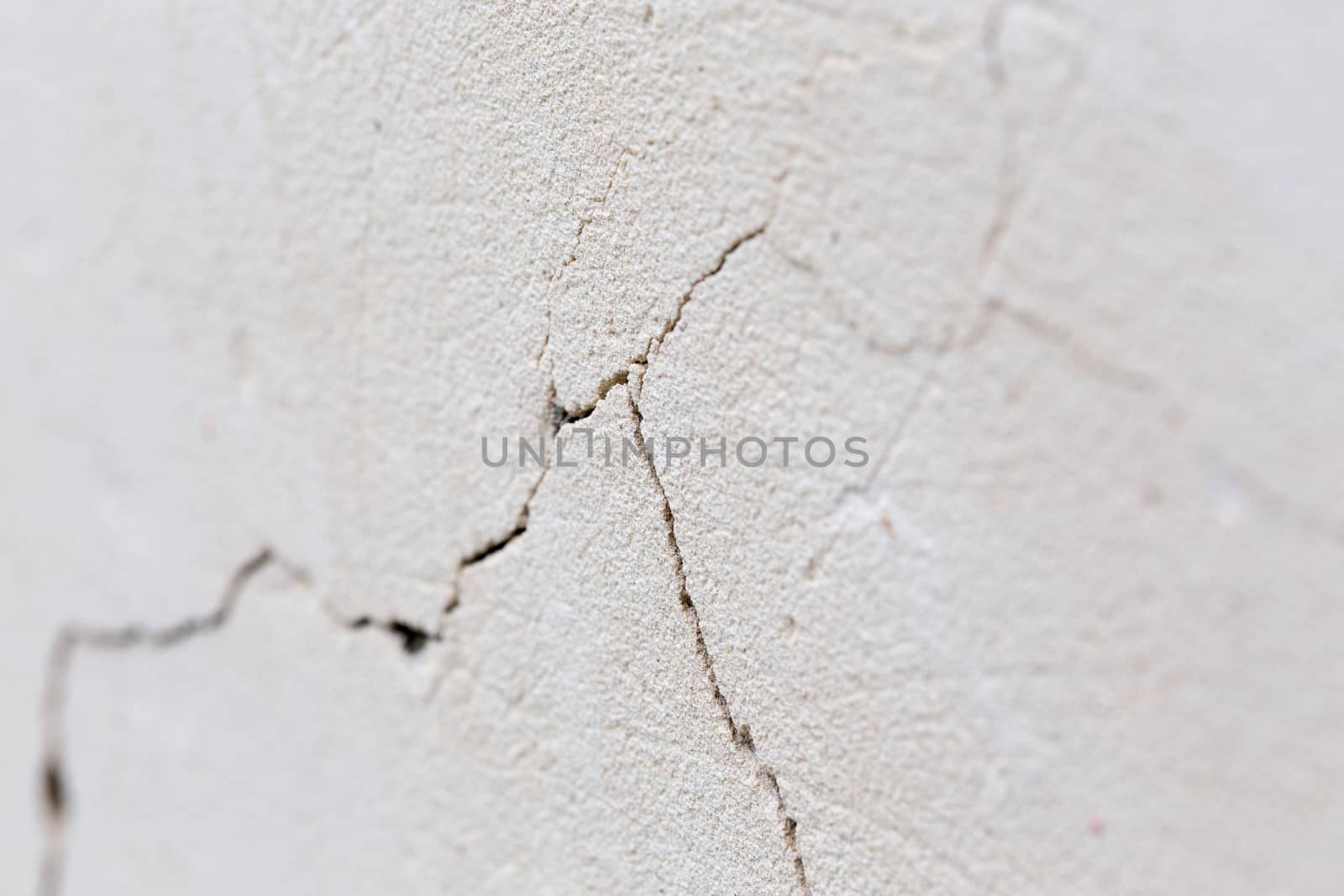closeup background of cracked light porple plaster wall with selective focus and naturla blur.