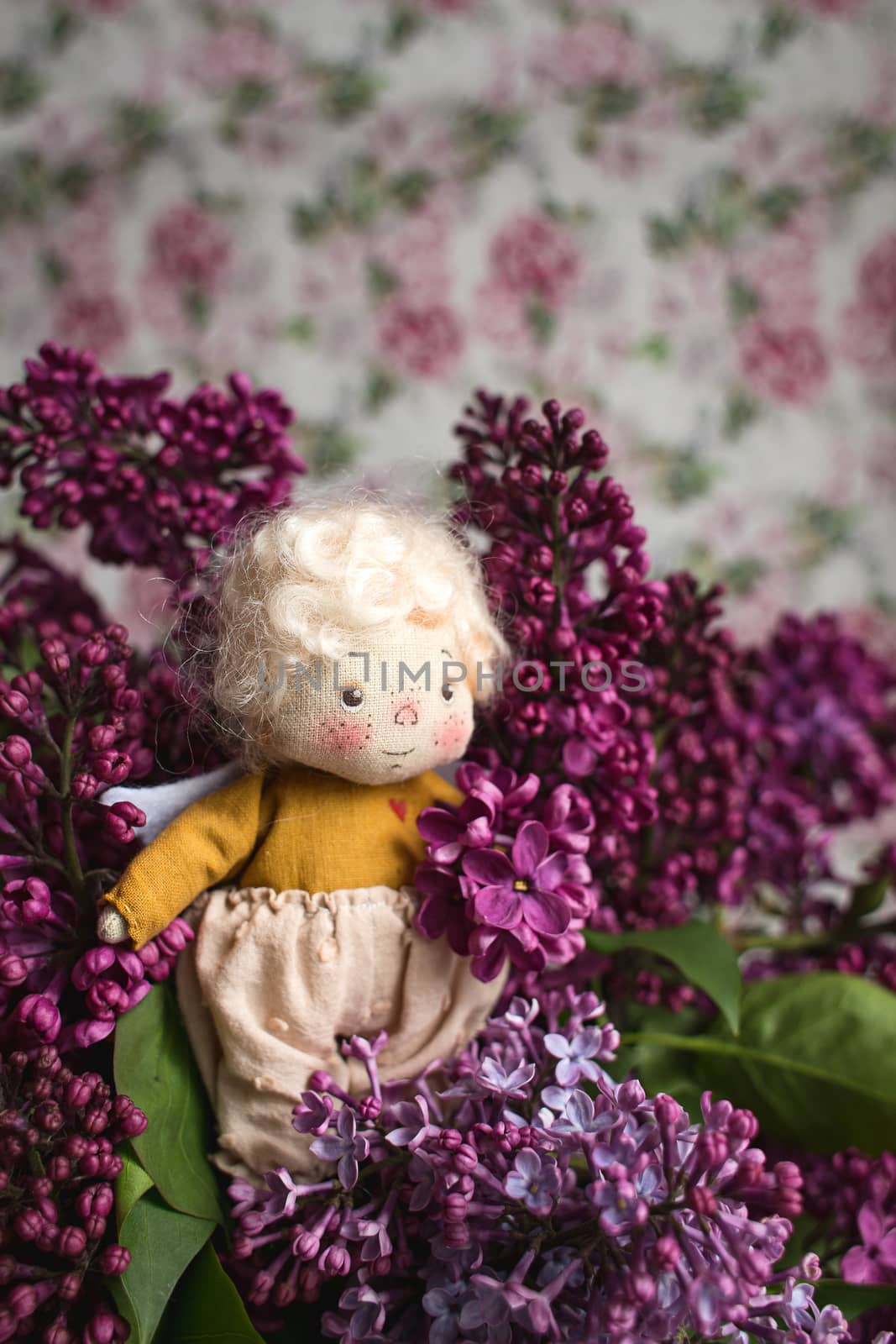 Little golden-haired angel in the blue, pink, purple, violet lilac flowers. Handmade toy in violet lilac colors.