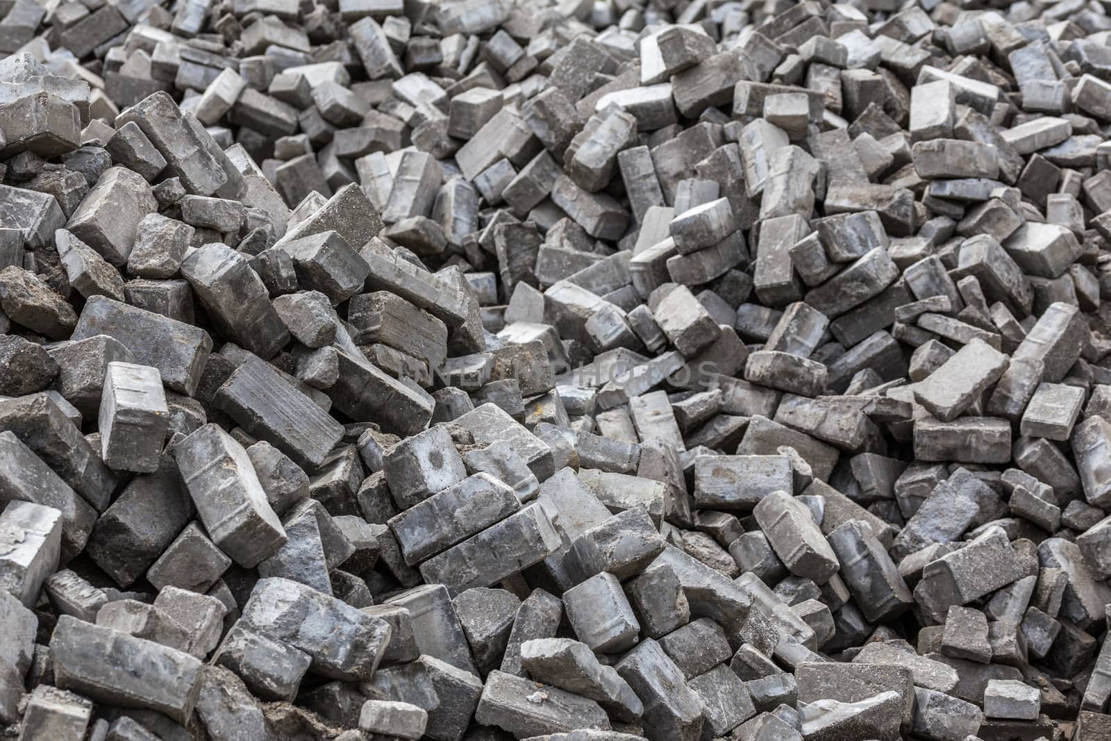 Pile of dismounted gray modern urban pavement bricks with selective focus. Result of russian government corruption in city infrastructure renovation.