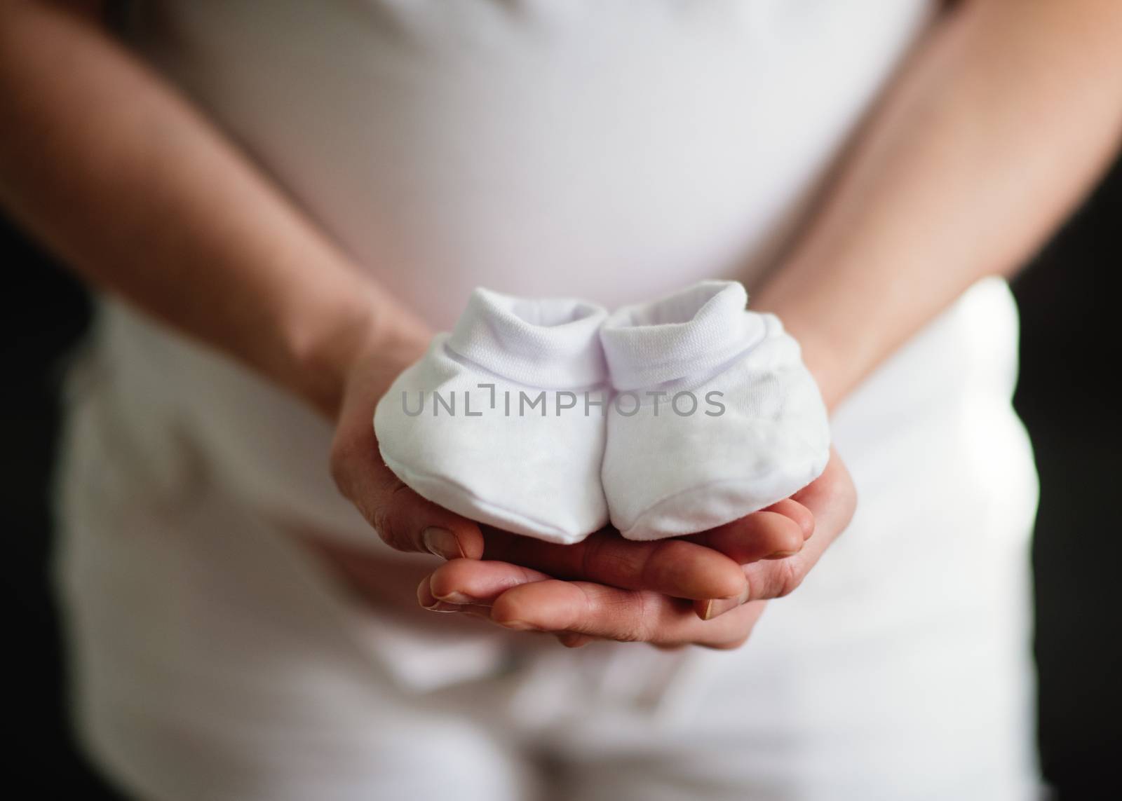 Pregnant woman holding baby shoes by Iryna_Melnyk