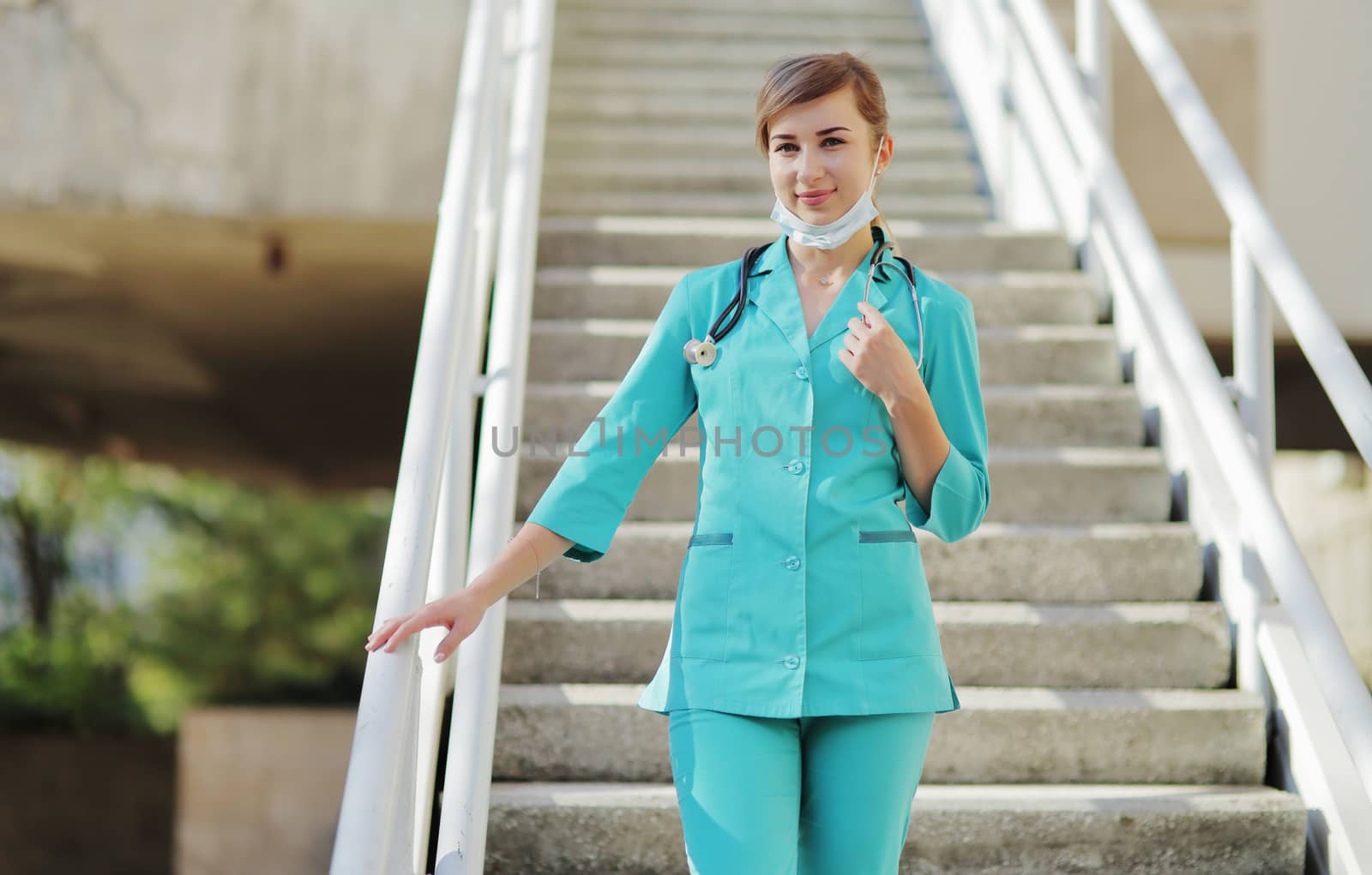 Female doctor or nurse in a protective face mask walking up the stairs by selinsmo
