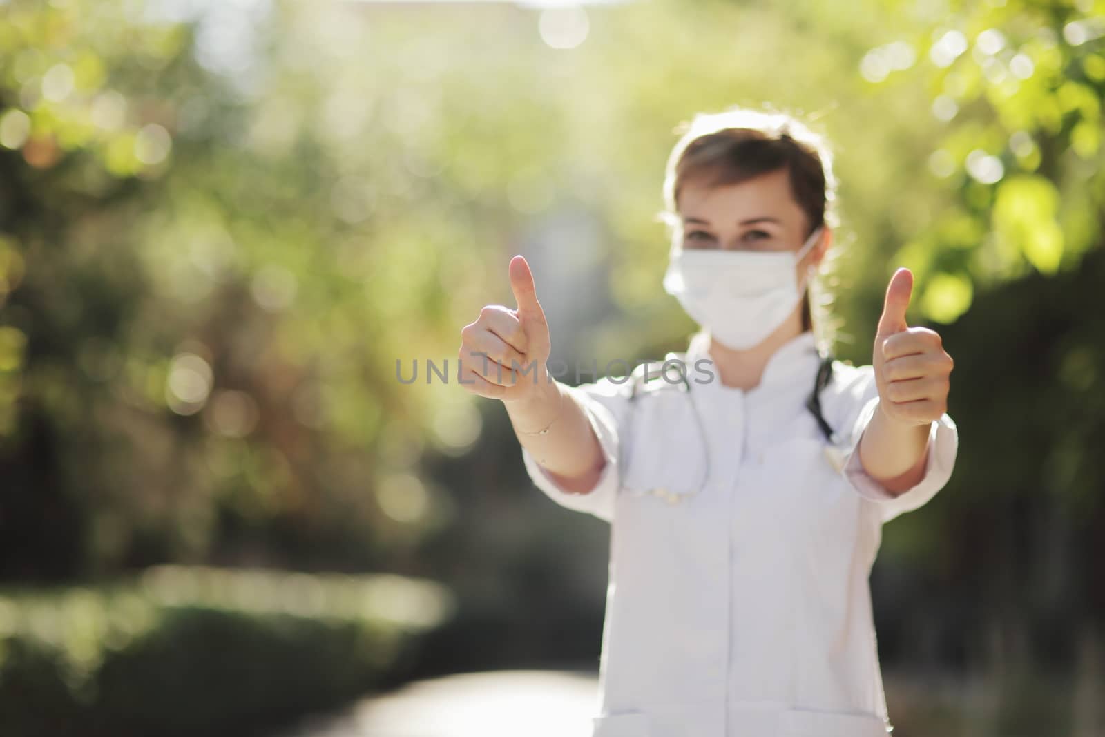 A female doctor or nurse in a protective face mask shows the class with her hand. Safety measures against the coronavirus. Prevention Covid-19 healthcare concept. Stethoscope. Woman, girl.