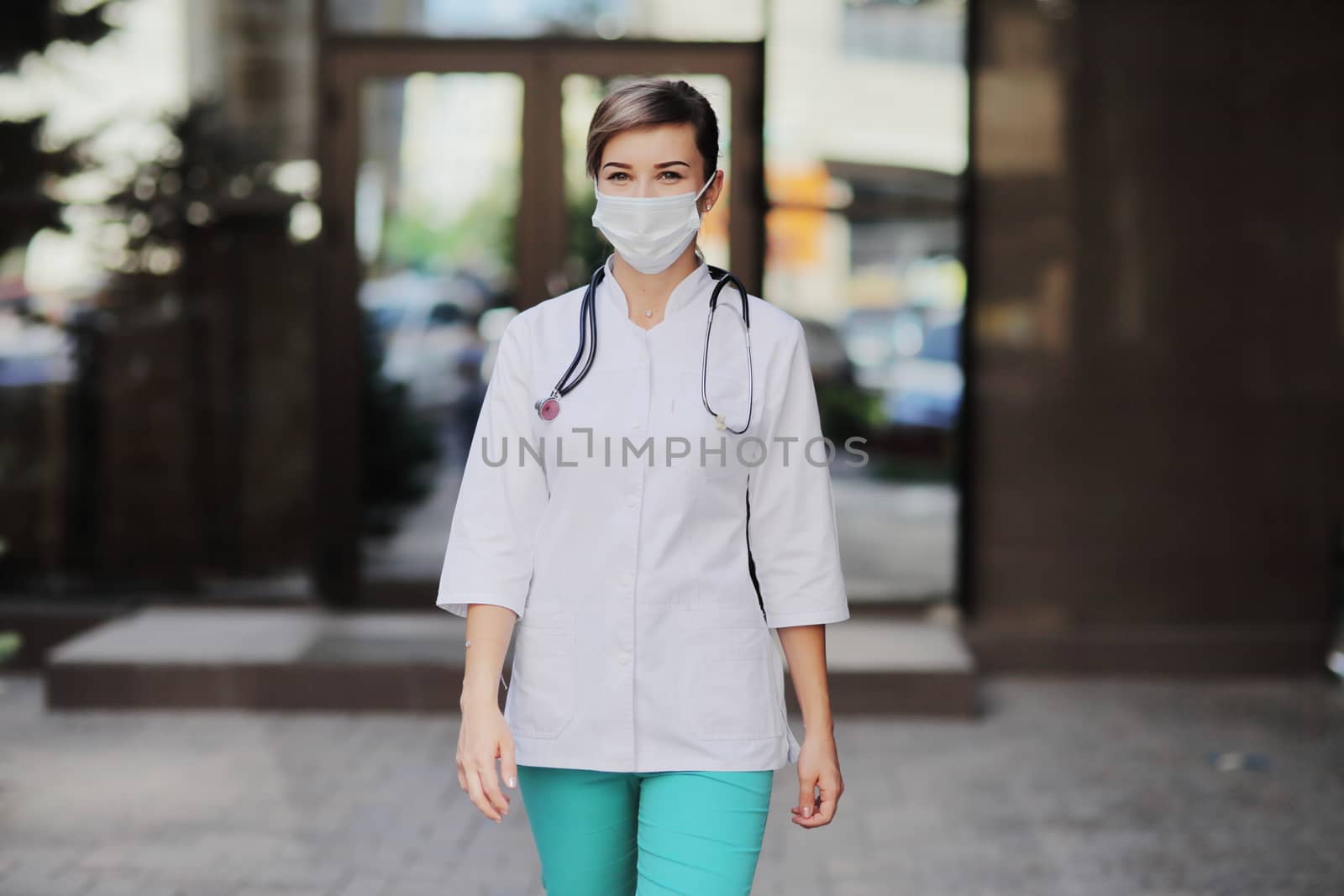 Confident female doctor or nurse wearing a face protective mask. Safety measures against the coronavirus. Prevention Covid-19 healthcare concept. Stethoscope over the neck. Woman, girl.