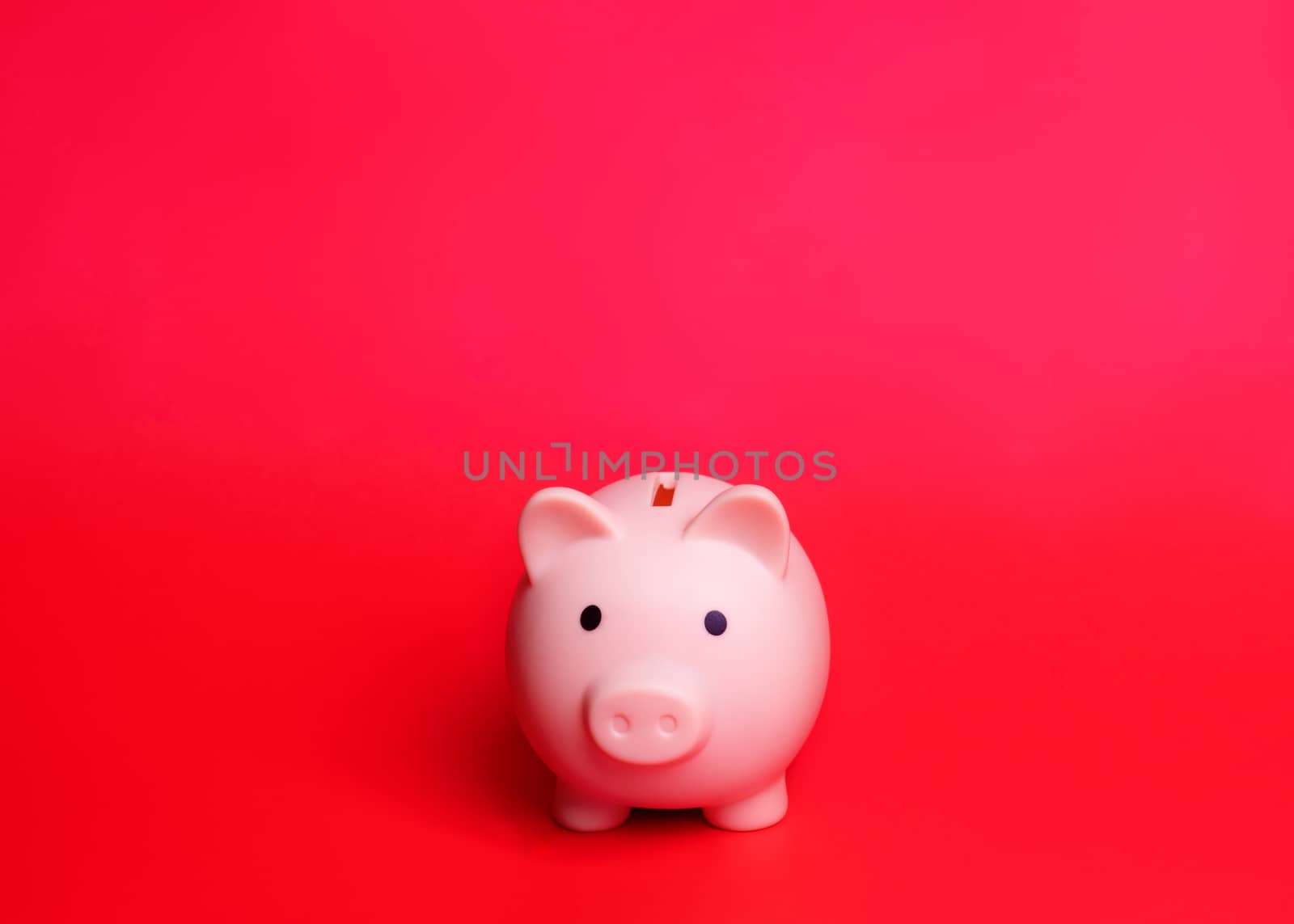 A Pink piggy bank isolated against red background