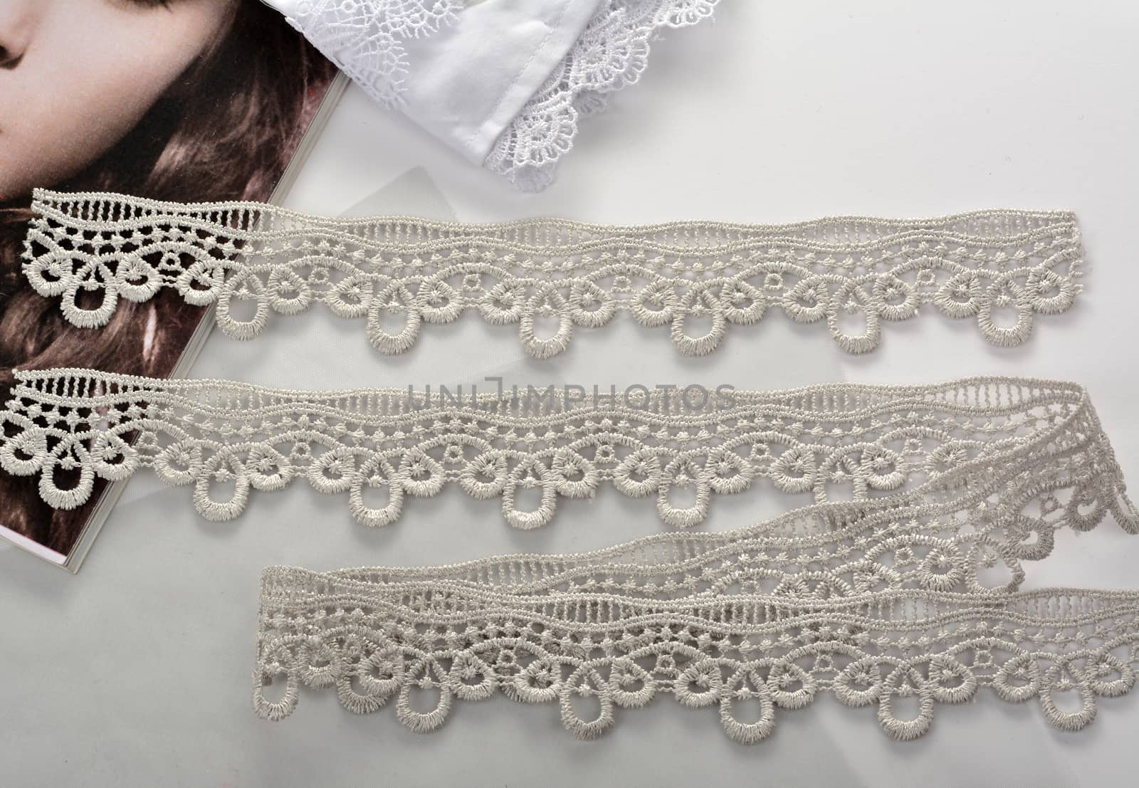 Tapes of gray gentle guipure, beauty lace fabric on light background. Elastic material. Using for Atelier and needlework store. Space for text