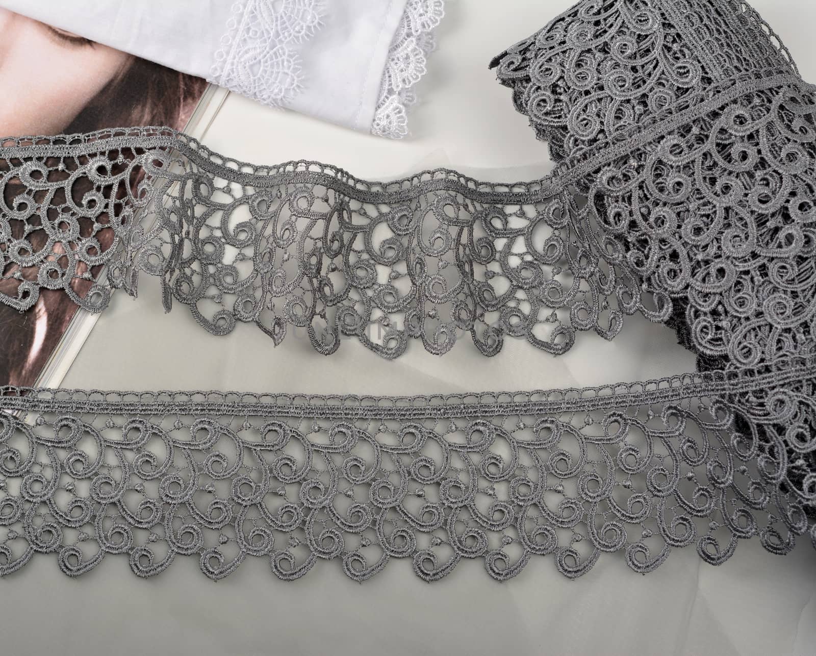 Tapes of gray gentle guipure, beauty lace fabric on light background. by polyats