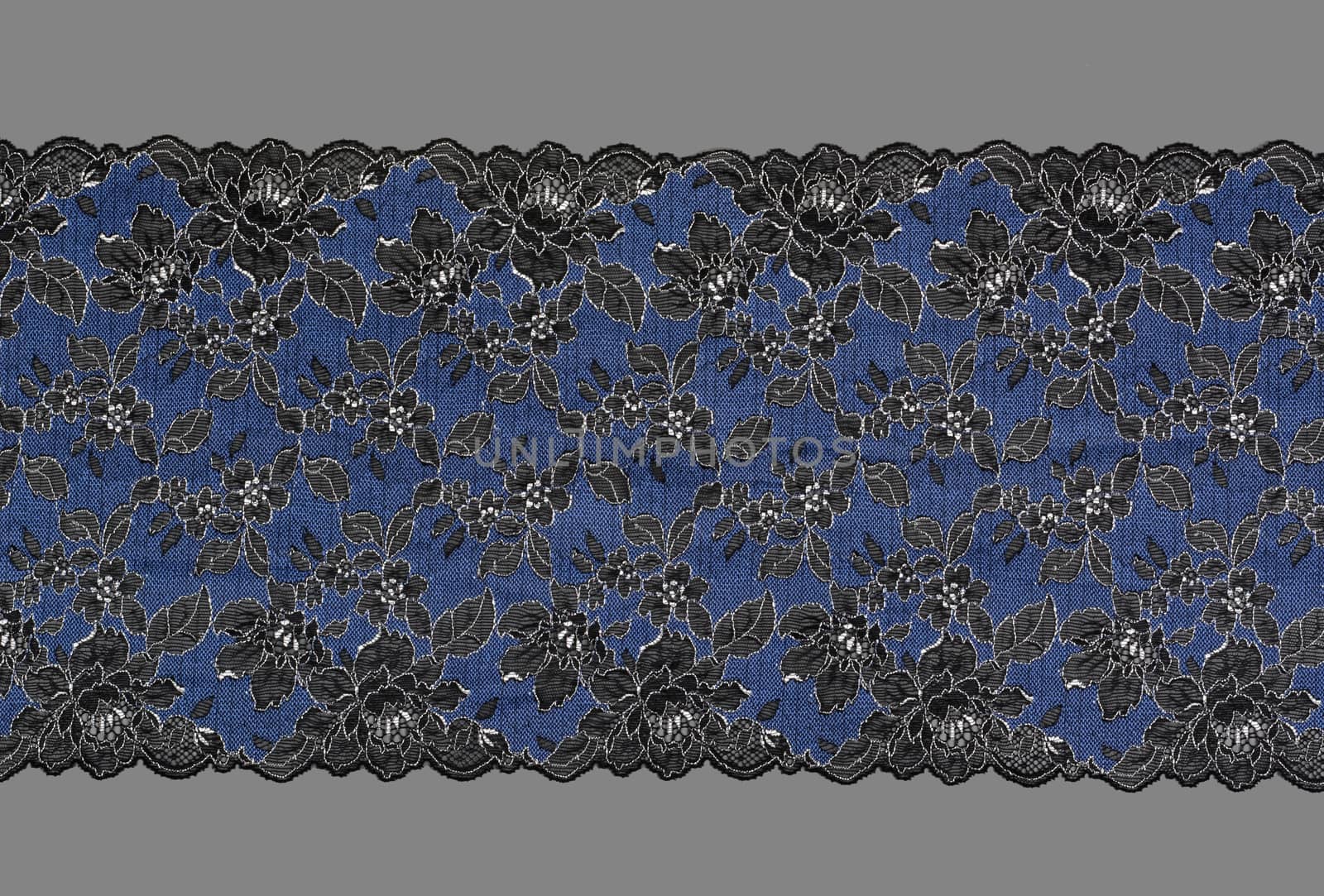blue and black color straight strip of lace fabric on gray background. Elastic silk nylon braid border. use clothes linen decoration. repeating pattern and interweaving threads. texture for websites