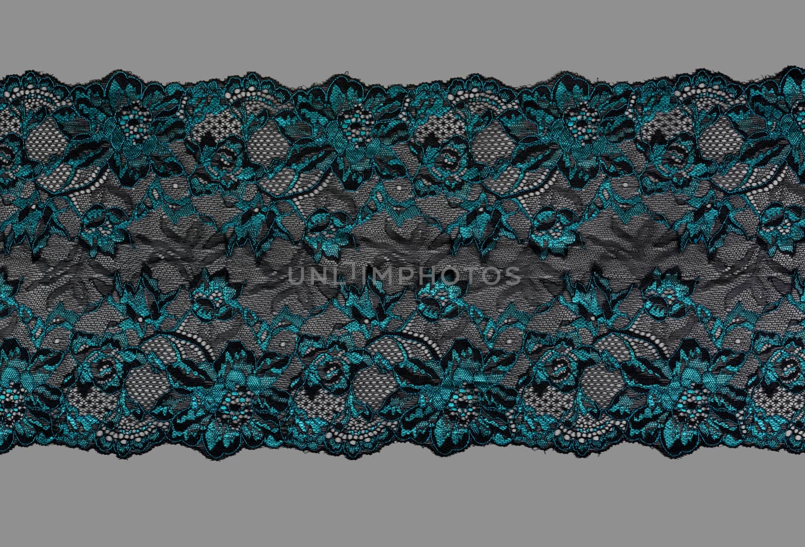 emerald black color straight strip of lace fabric on gray background. Elastic silk nylon braid border. use clothes linen decoration. repeating pattern and interweaving threads. texture for websites