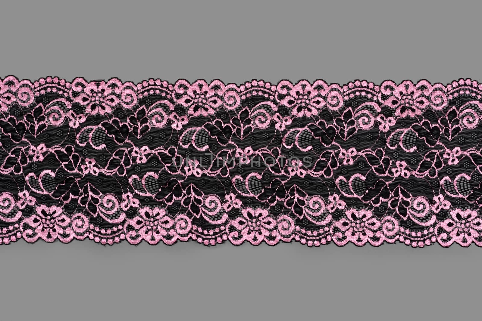 pink black color straight strip of lace fabric on gray background. Elastic silk nylon braid border. use clothes linen decoration. repeating pattern and interweaving threads. texture for websites