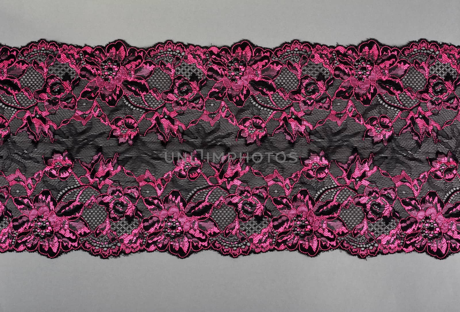 pink black color straight strip of lace fabric on gray background. Elastic silk nylon braid border. use clothes linen decoration. repeating pattern and interweaving threads. texture for websites