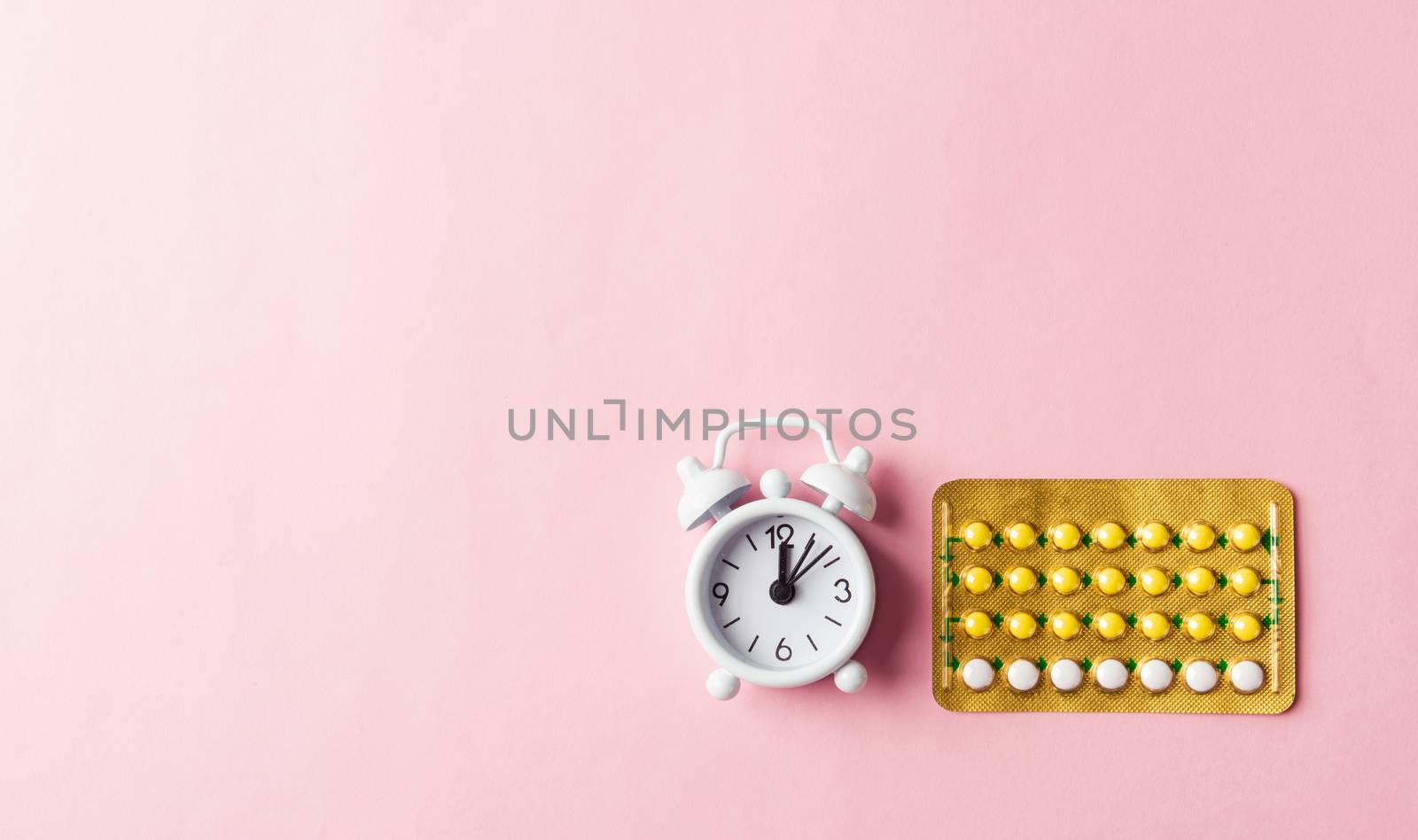 World sexual health or Aids day, Top view flat lay medicine birth control, alarm clock and contraceptive pills, studio shot isolated on a pink background, Safe sex and reproductive health concept
