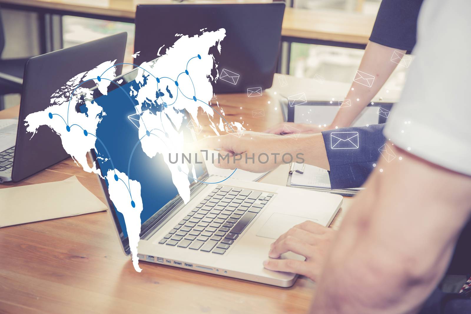 Sending email, gesture of finger pressing send button on a computer keyboard on world map with people in office, communication concept, Elements of this image furnished by NASA.